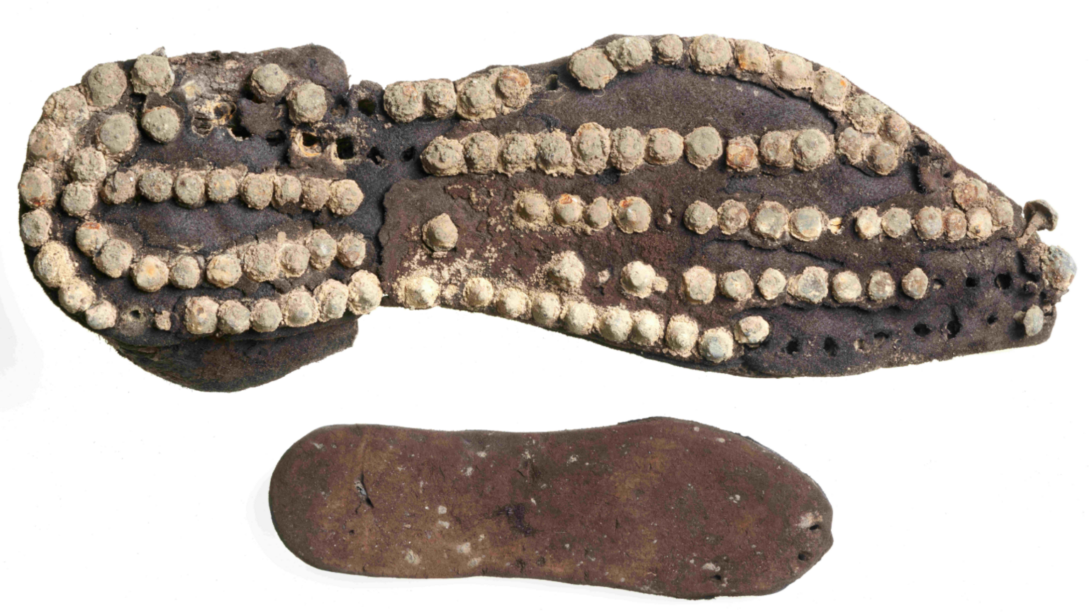 Roman leather shoes belonging to an adult and a child. The top image shows the adult leather shoe - which looks like the sole of a modern day shoe -  with what looks like several round white studs all over it and the child's shoe is dark brown leather with no similar markings like the adult shoe.