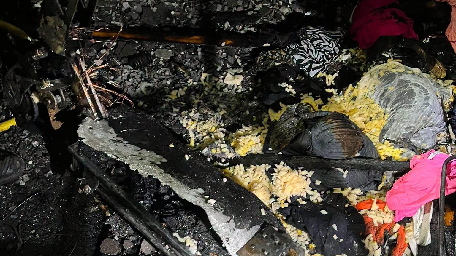 A pile of burnt items on the floor, like clothes
