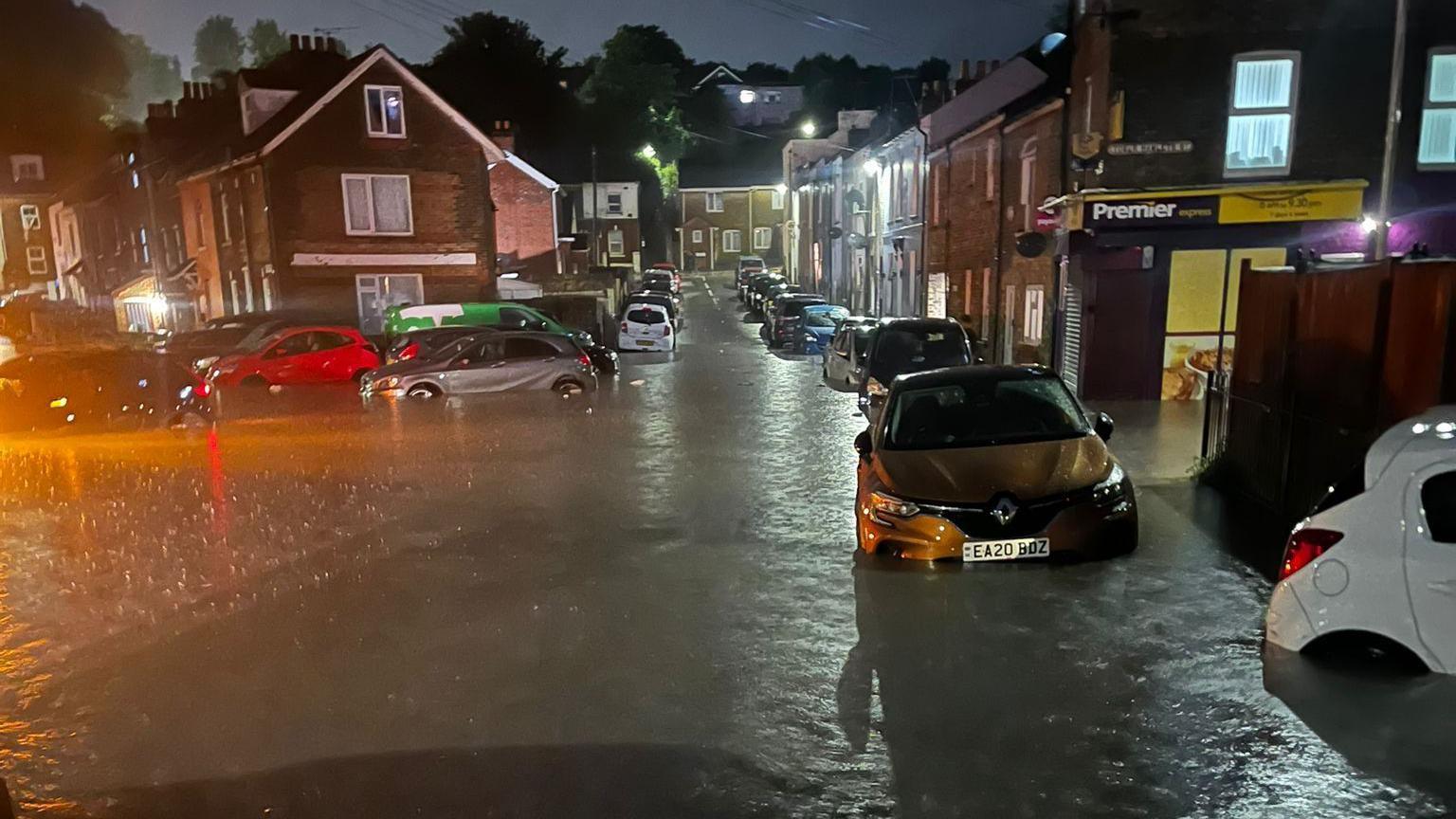 Cars are submerged in flood water on a residential street