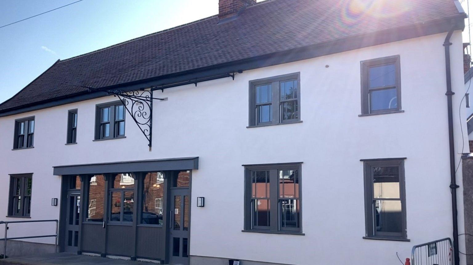 A pub with white walls and grey doors is bare and without signage after reopening.