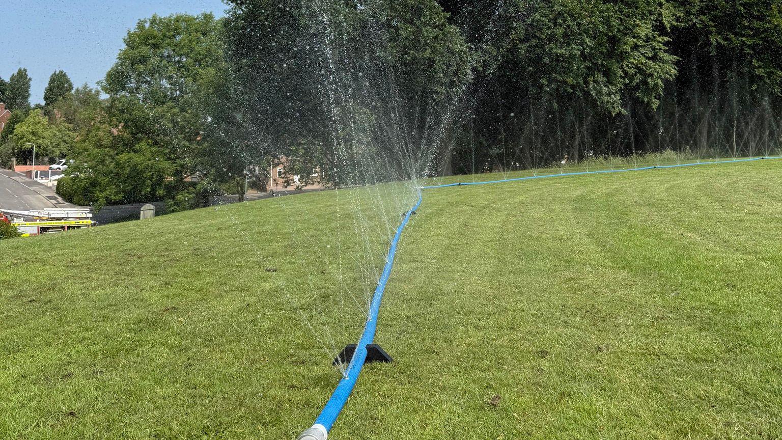 a perforated blue hose which shooting water eight metres into the air