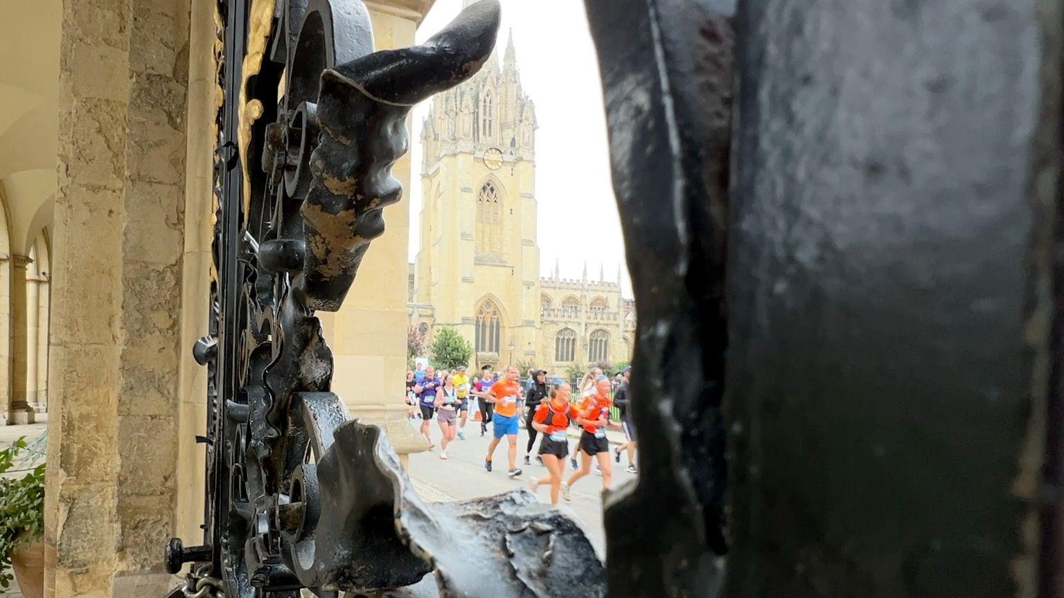 Runners can be seen through an iron gate in Oxford.