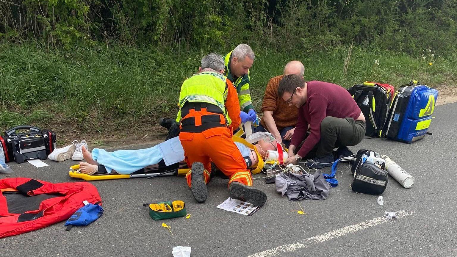 Paramedics and two off-duty doctors crouching around and treating Harry Pyett, who is lying on a stretcher on the ground.