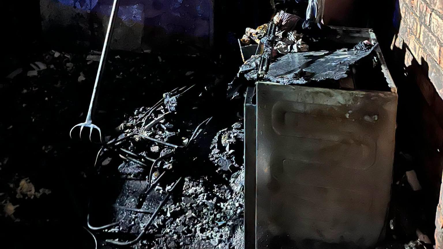 A burnt appliance on the right and on the left are burnt items which are hard to identify