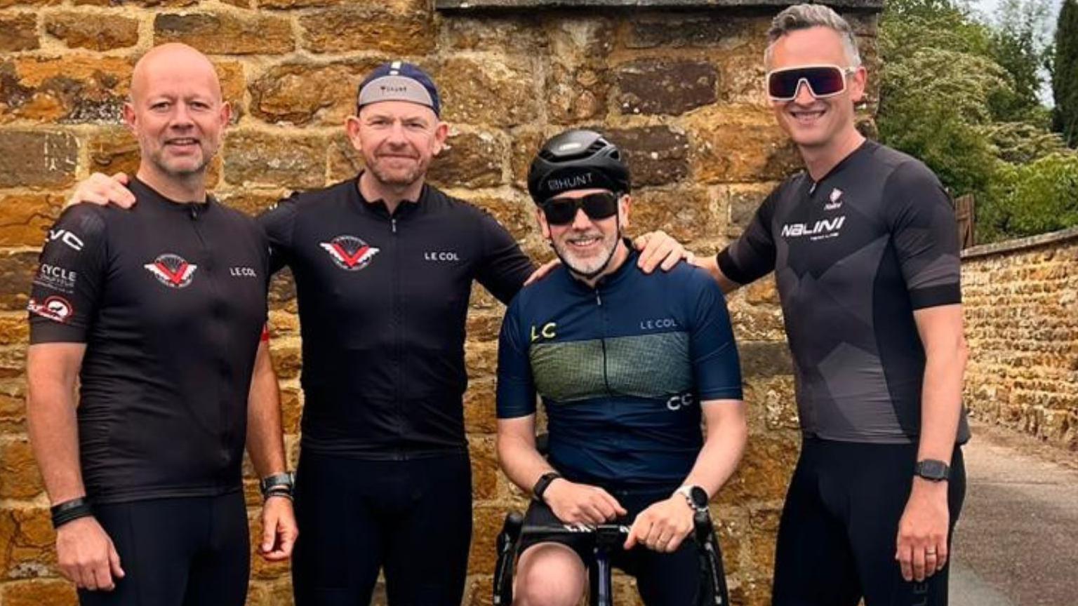 Four men pictured together while wearing cycling gear.