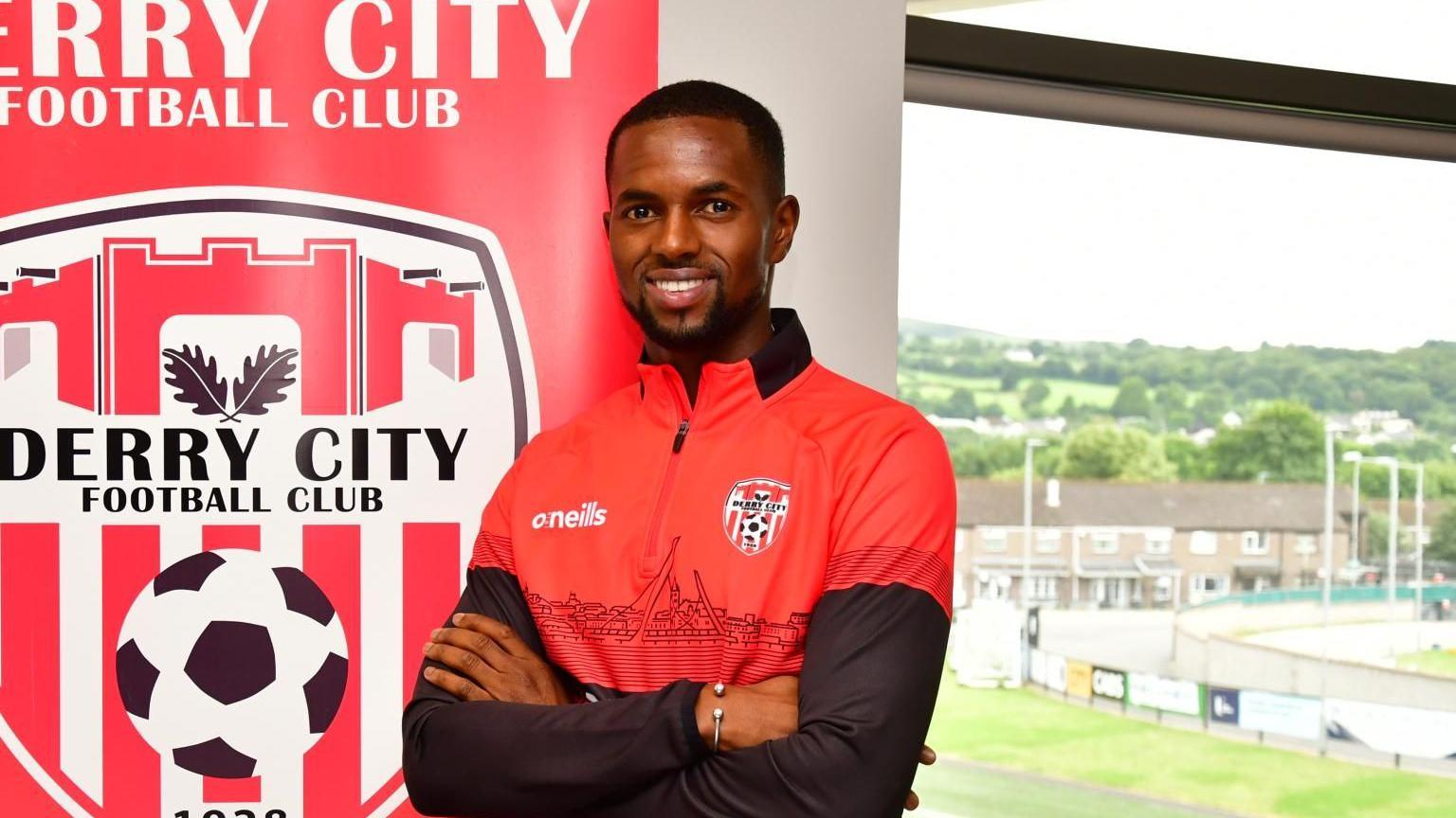 Shows Sadou Diallou with Derry City emblem and Brandywell in the background