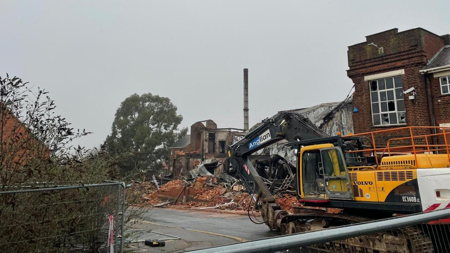 Demolition plant alongside piles of red bricks