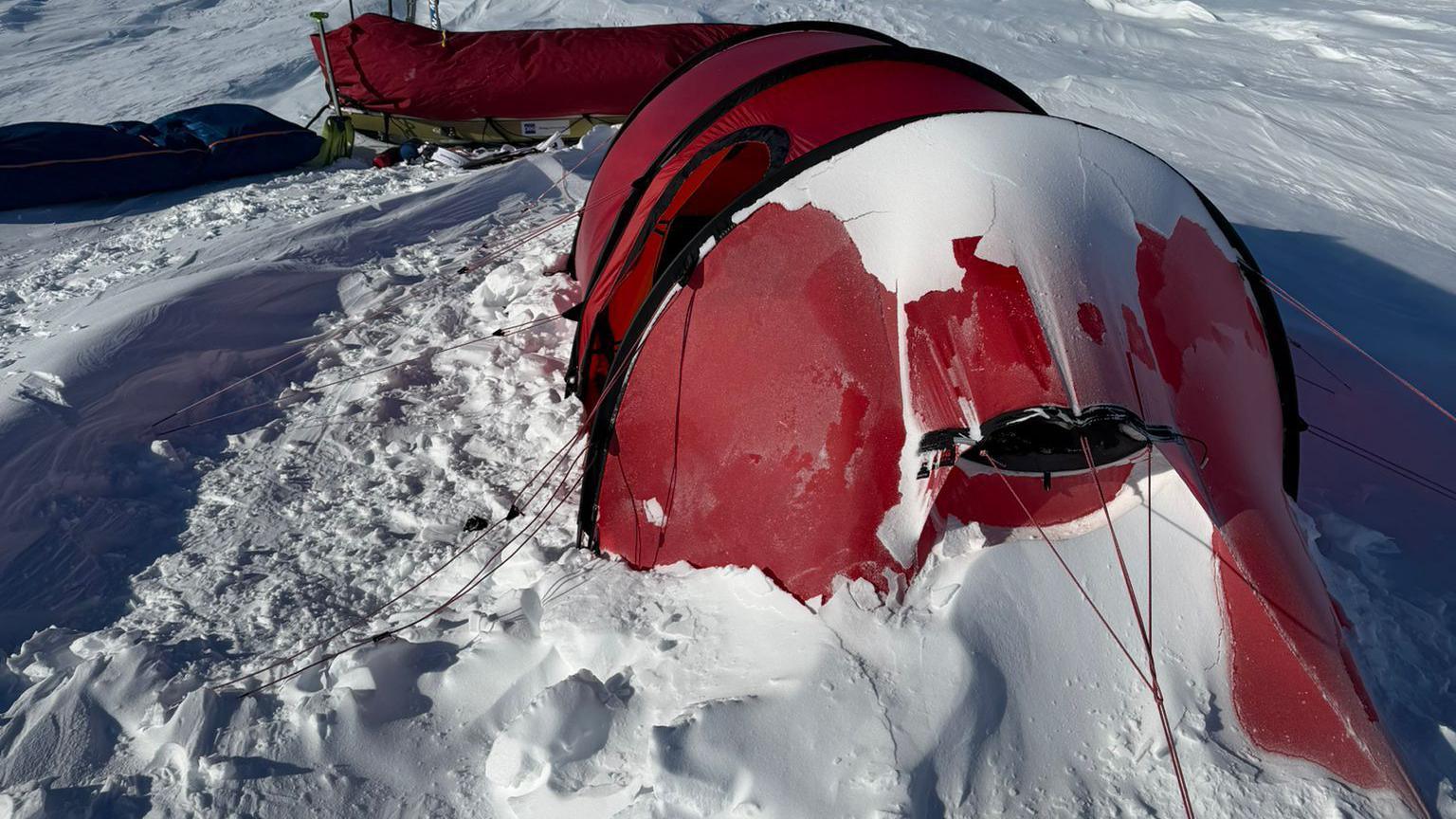 Ian's red tent caked in snow around it and on parts of the top.