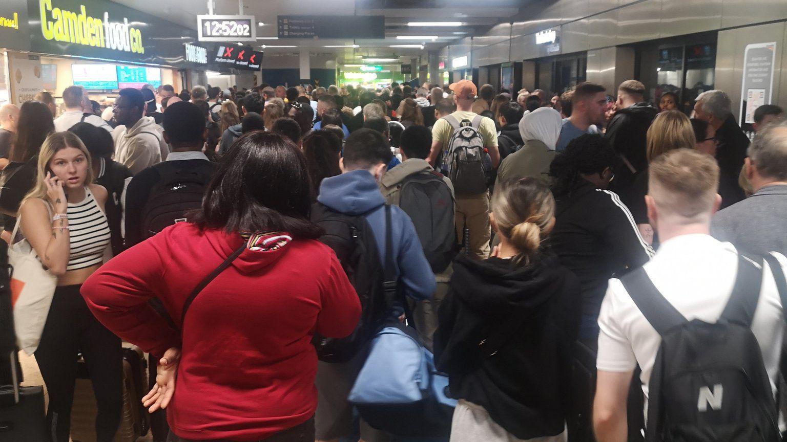 A crowd of rail passengers waiting at Euston station