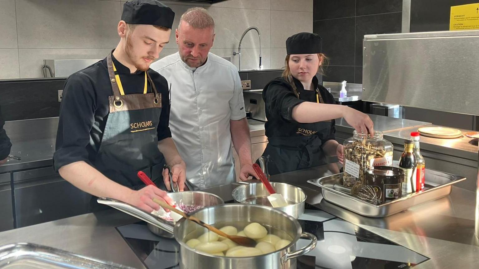 James Ashworth (19) (left) Sophie Wilkinson (18) David Lyon (centre) head chef and tutor at Blackburn college - cooking in the new kitchen