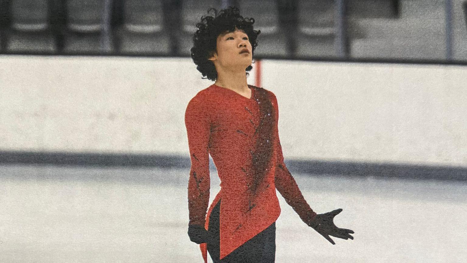 Spencer Lane, a young man with curly black hair, skates wearing a red and black costume.