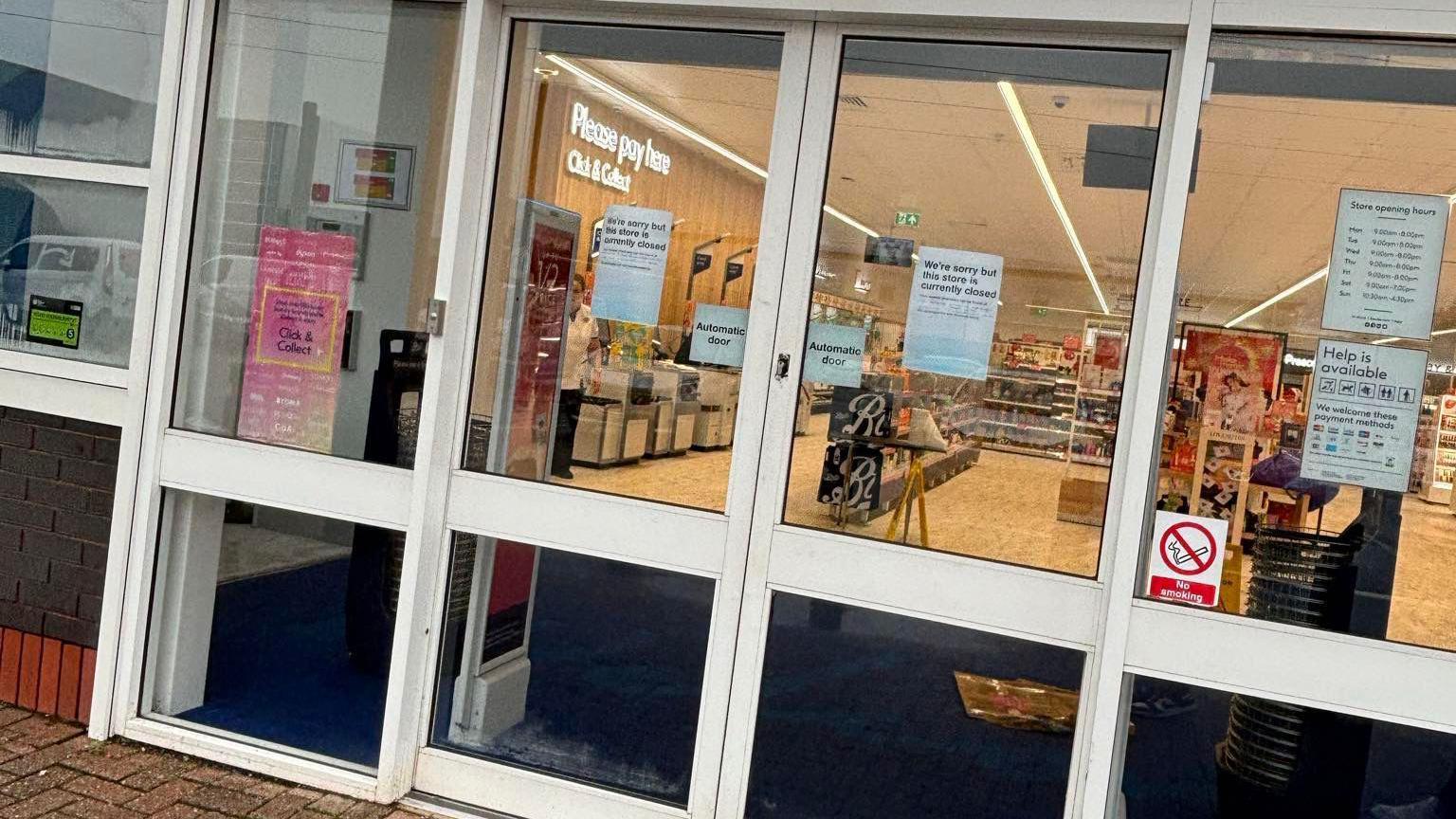 The front doors of Boots a shop, with signs on saying "we're sorry, but the store is currently closed". 