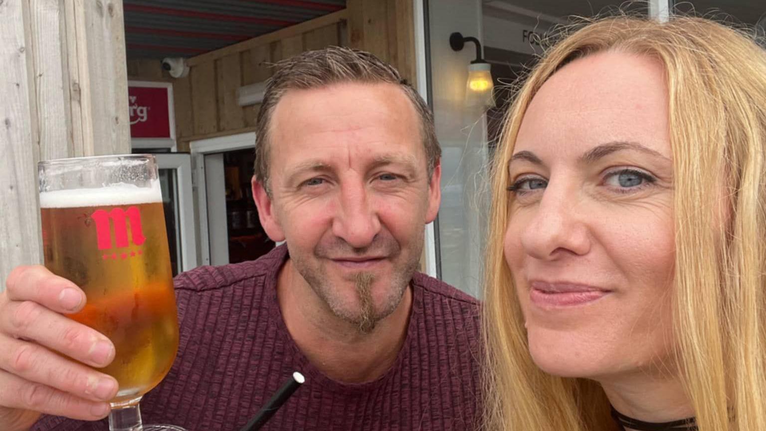 Nataliya Tailistyler and Matthew Boylan smiling at the camera. He is holding a pint of beer in his left hand.