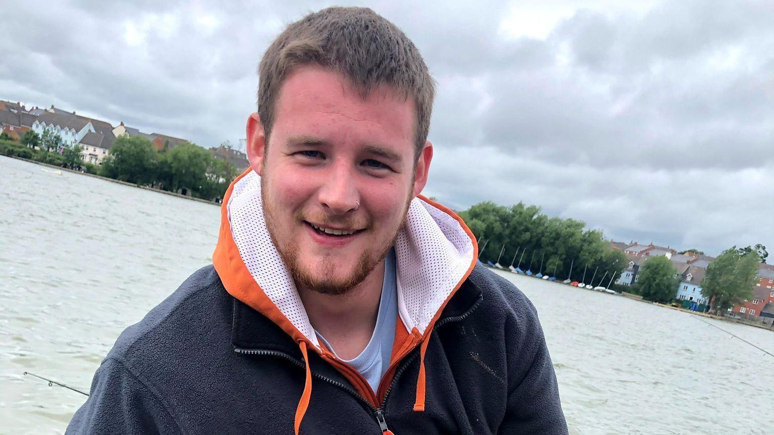 A man smiling in a boat on a lake