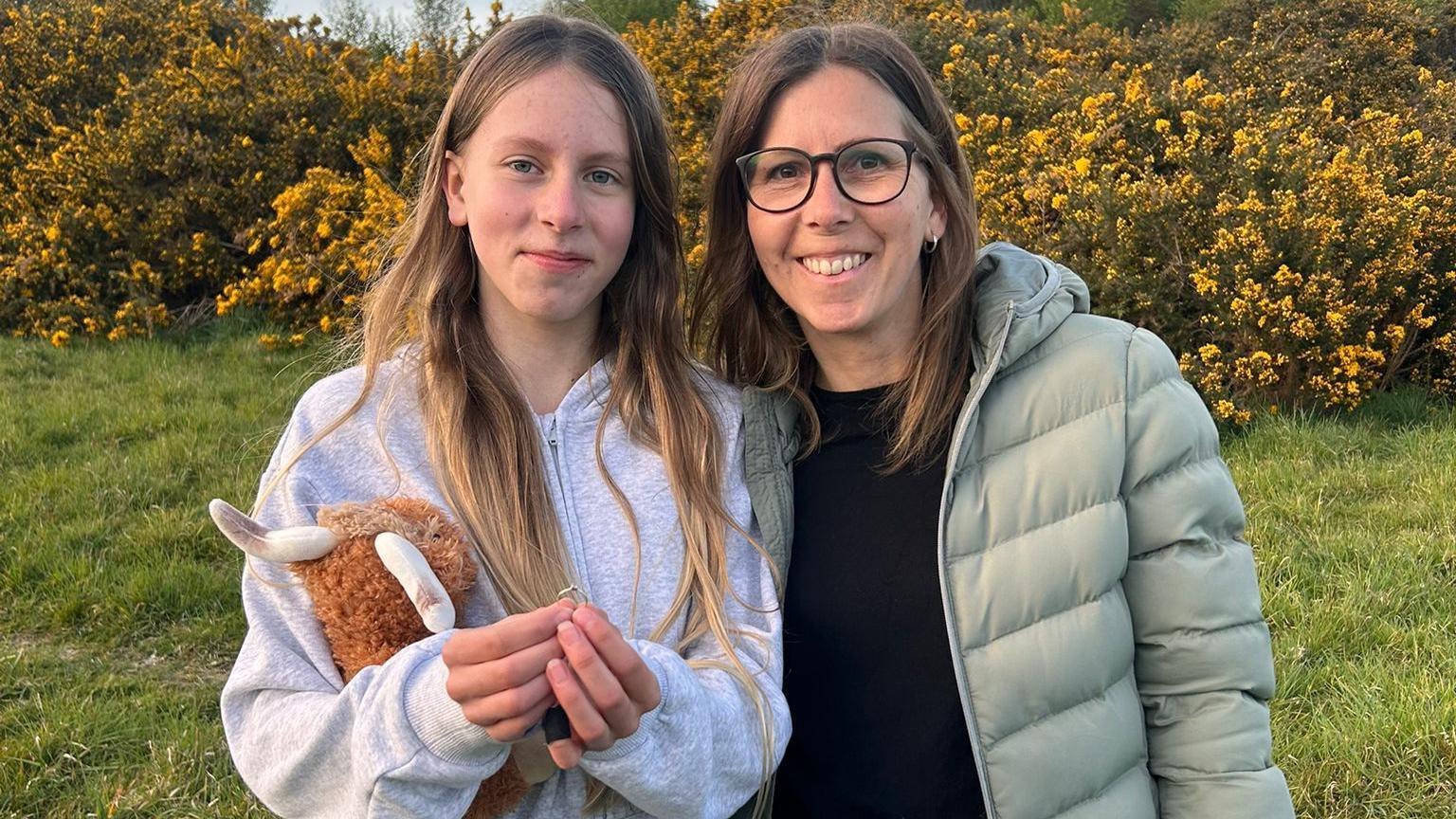 Maxine (right) and her daughter Poppy (left) holding a ring while standing in a garden