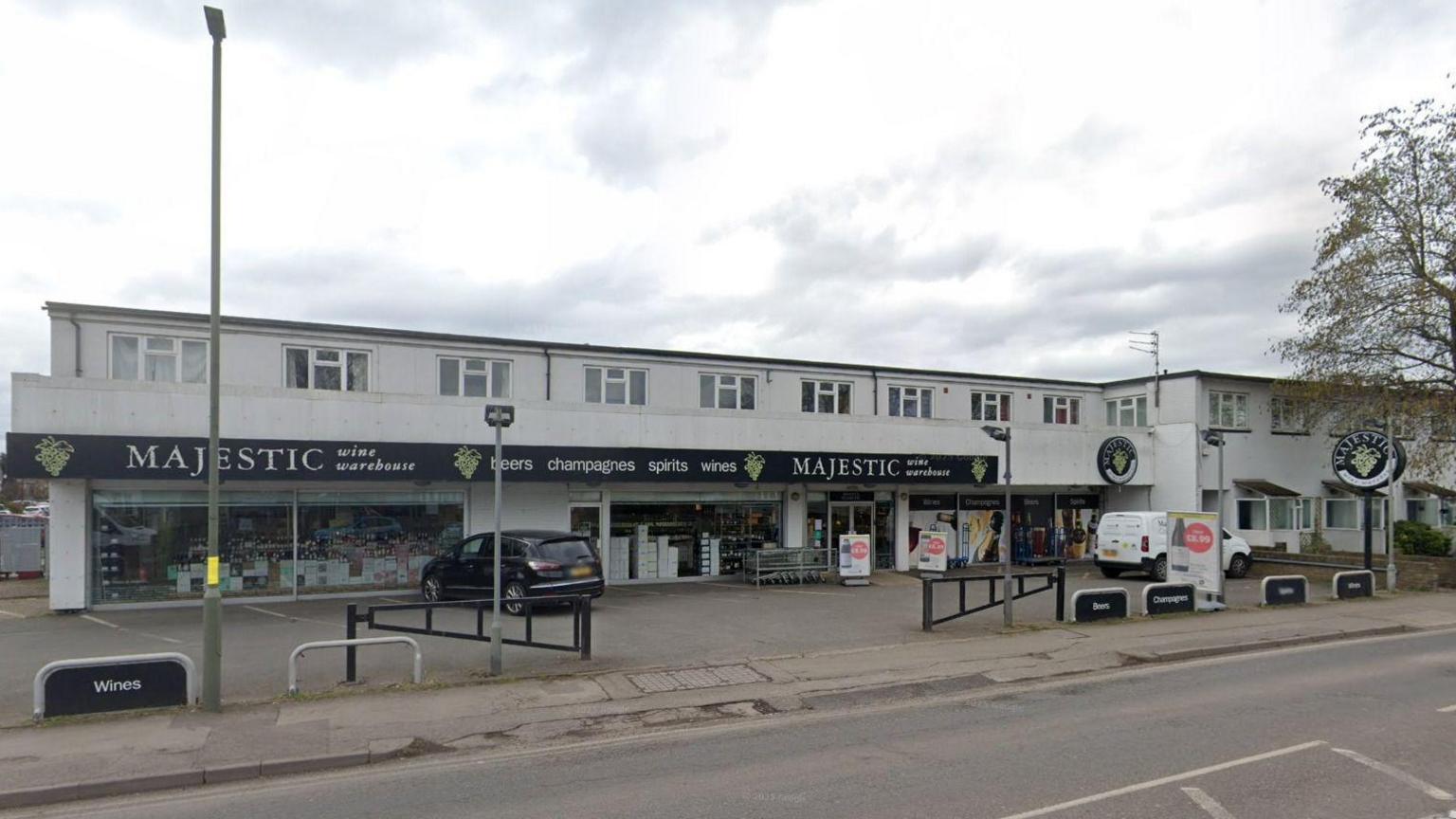 A wine shop in Molesey, Surrey. There is a black car parked outside the shop.