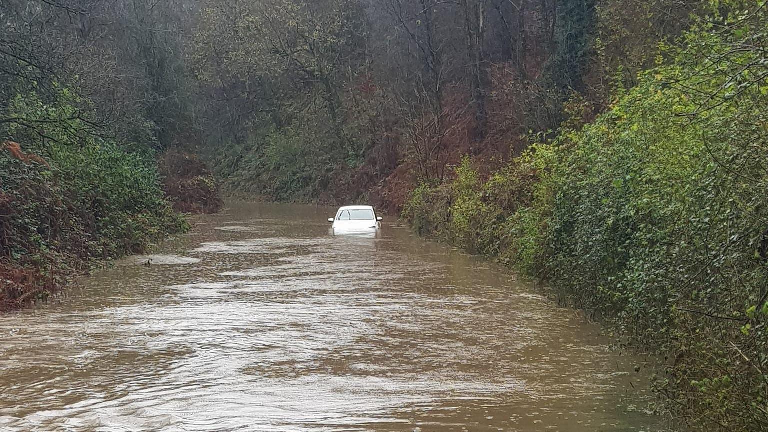 A car is stuck on a flooded road.