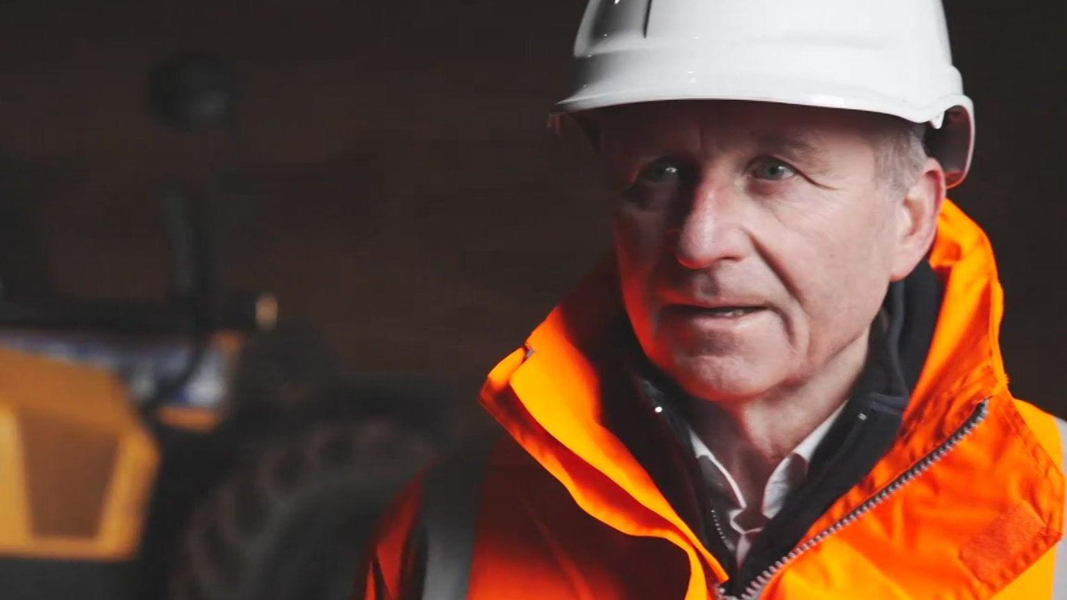 James McCoy wearing a white hard hat with orange high visibility jacket