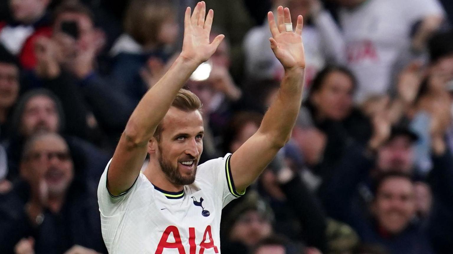 Harry Kane smiles as he raises his arms in celebration while playing for Tottenham
