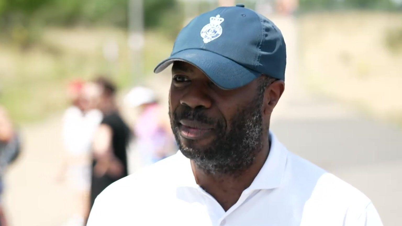 Omosuyi Fred-Omojole, who is wearing a green cap and a white tennis shirt