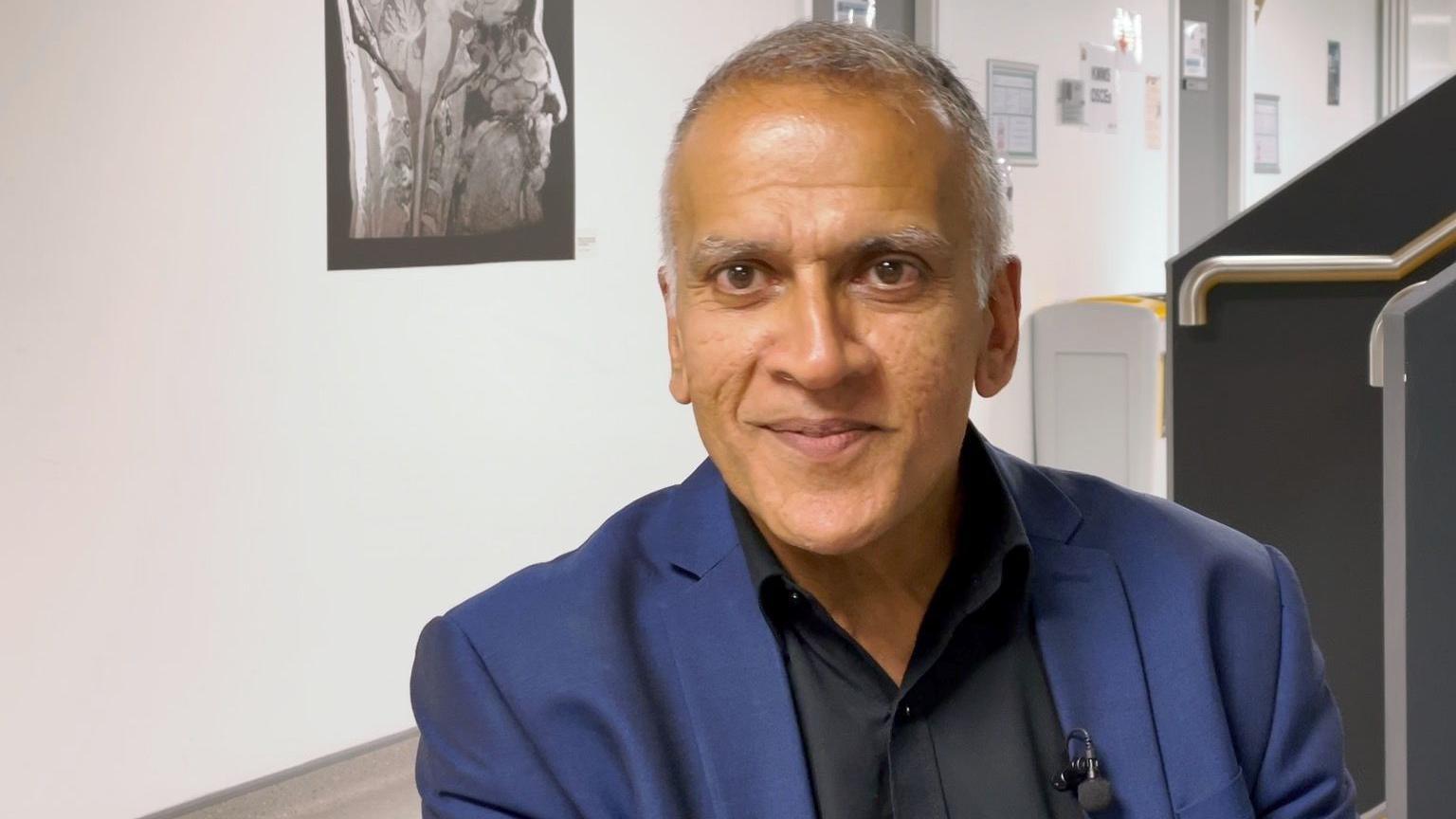 A man with short grey hair and a blue jacket