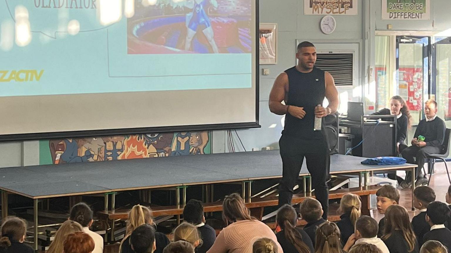 An image of Zack George giving a speech to children at Woodbridge Junior School