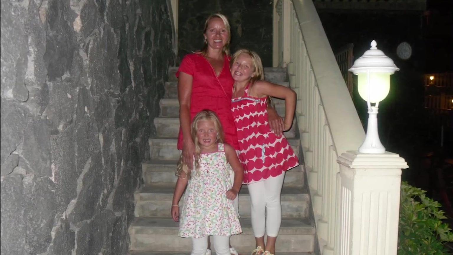 Julie stands on some steps with her two daughters 