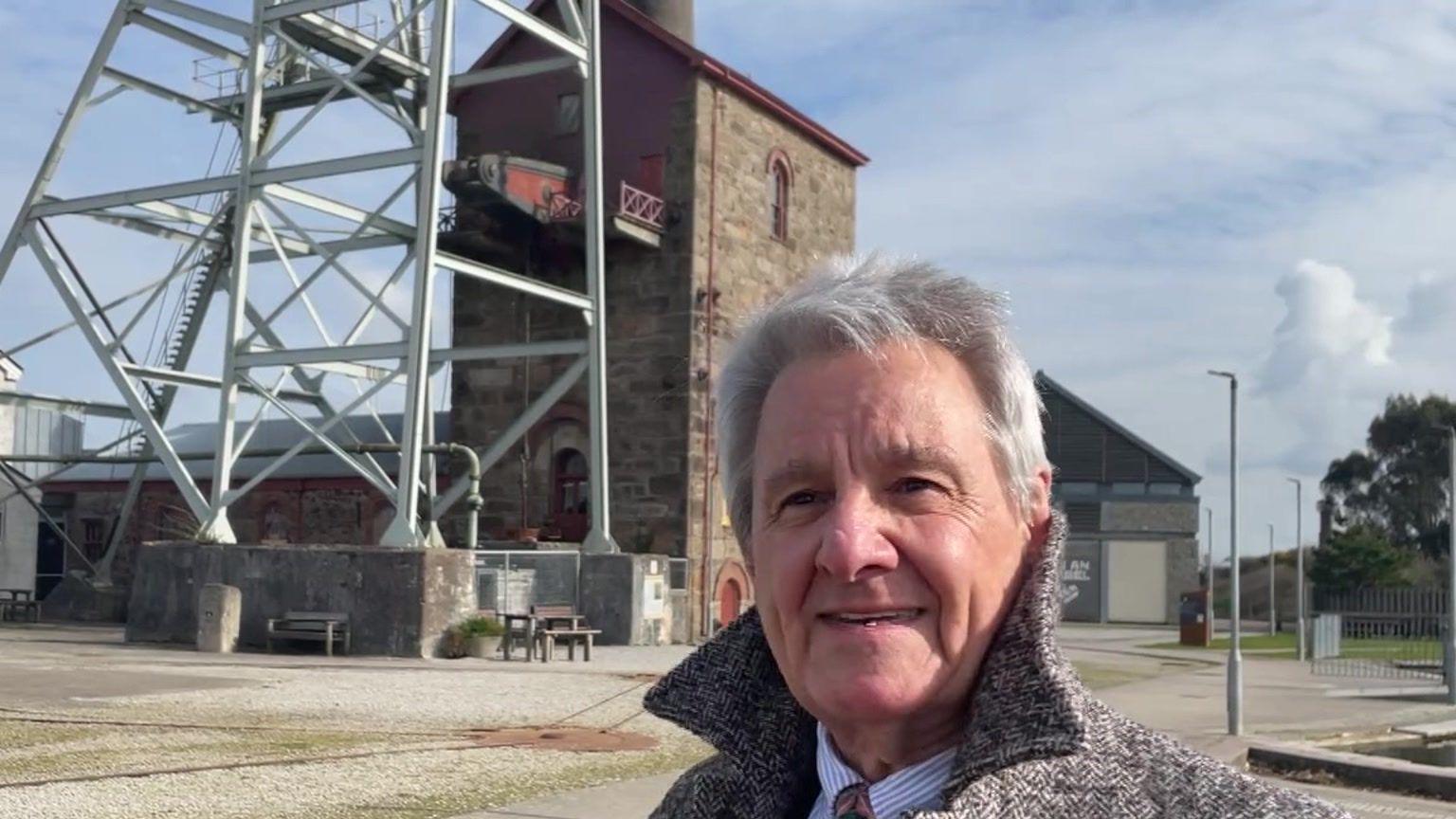 Man with grey coat standing in front of old mining engine house at Heartlands in Pool