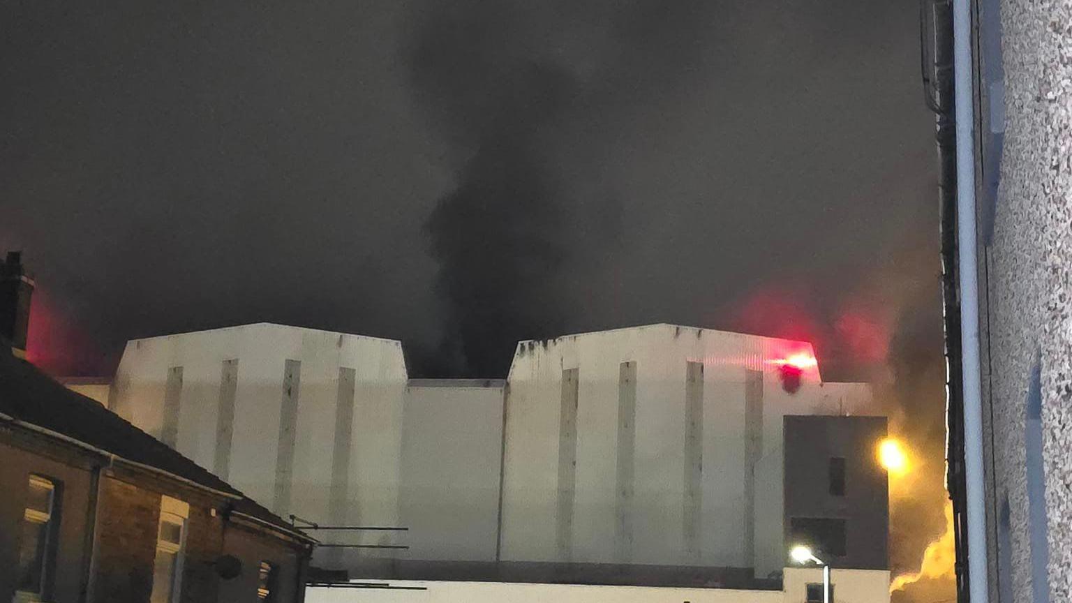 Smoke coming out of a large white building at the BAE Systems nuclear submarine shipyard. 