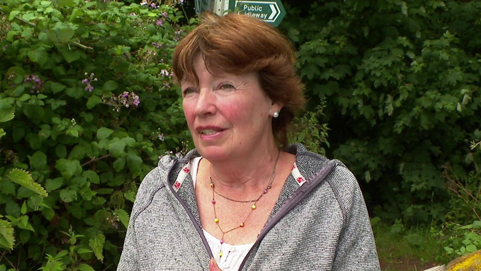 Claire Dummett standing in front of hedges 