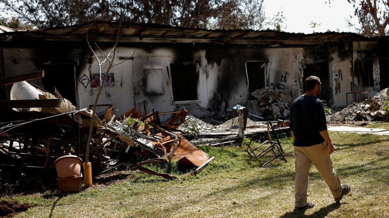 A resident of Israel's Kibbutz Nir Oz walks in front of houses burnt during Hamas's attack on 7 October 2023. Photo: March 2024