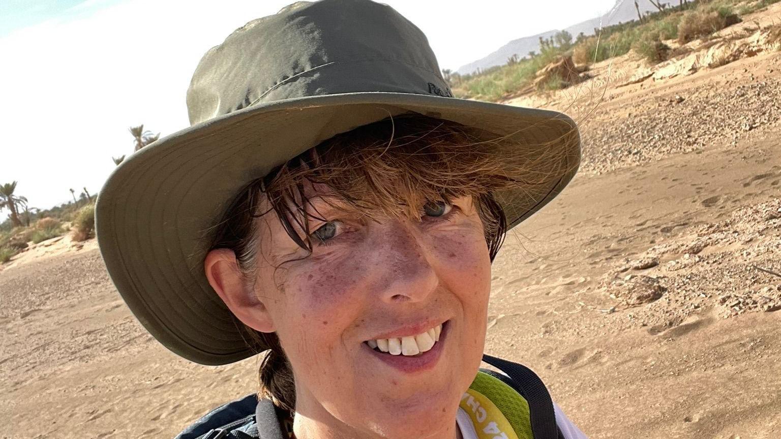 Walker Coleen Coxon is pictured in the Sahara desert wearing a sun hat during her marathon 