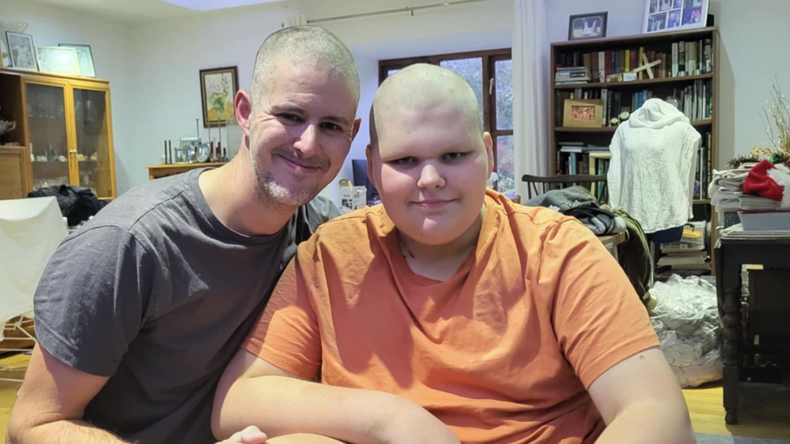 Picture of Louis (right) and his dad Ben smiling at the camera after shaving their heads. 