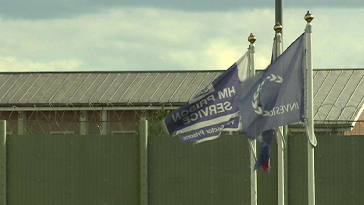 Flags flying outside a barbed wire topped fence