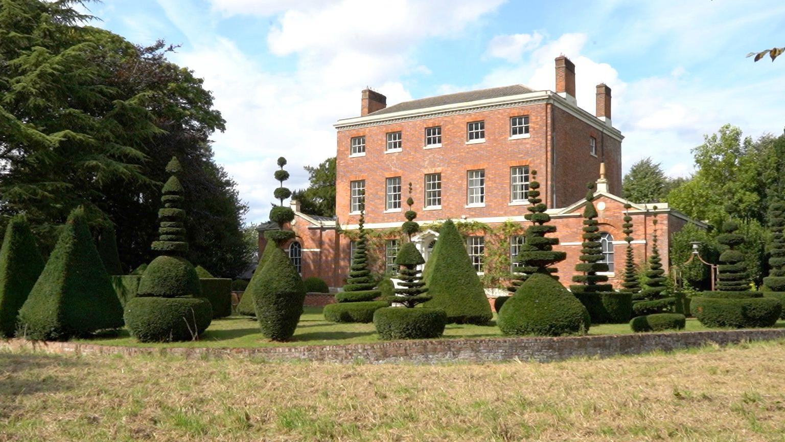 Front of Cressey Hall and gardens showcasing many different topiary designs