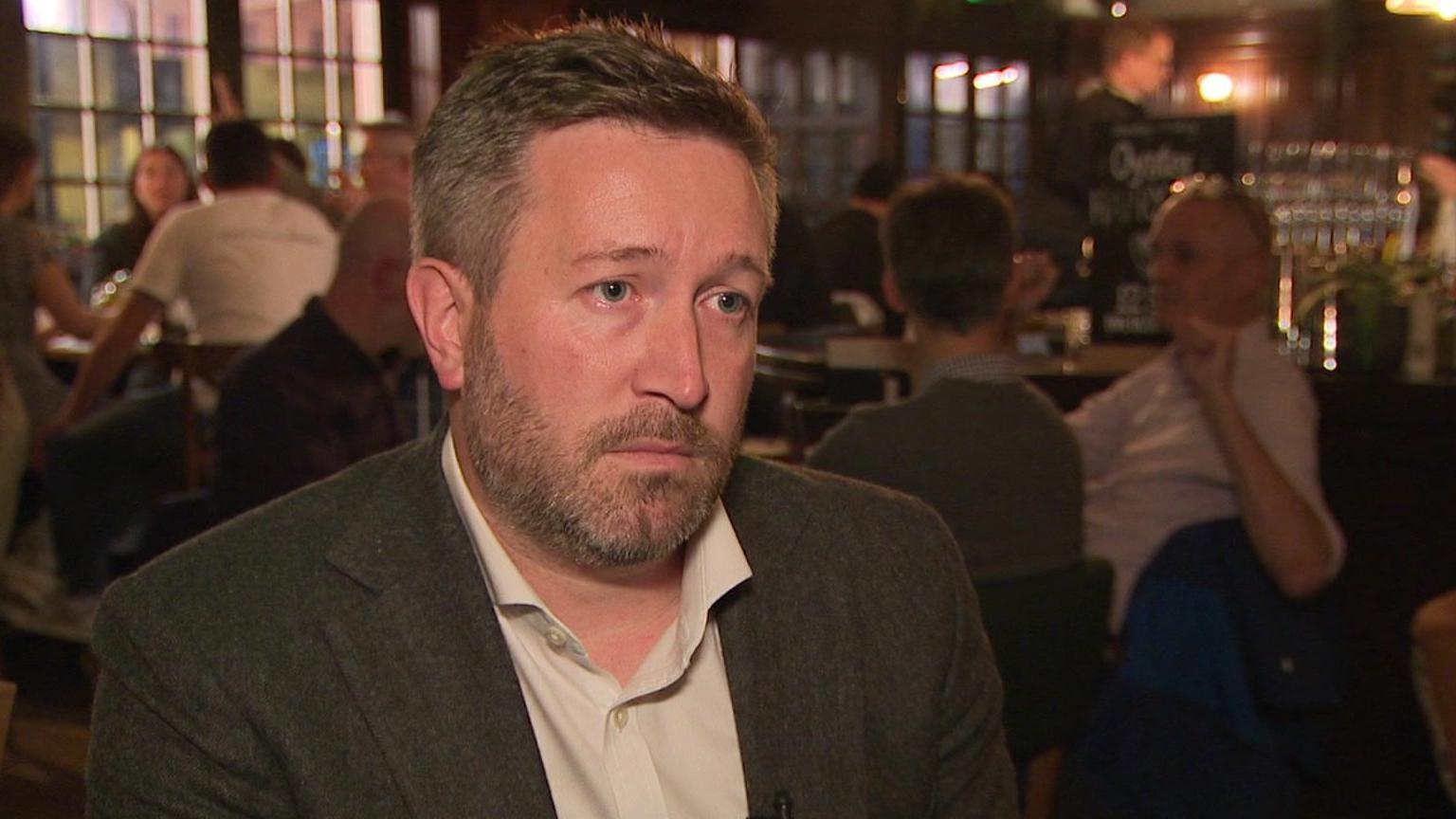 Anthony Pender, owner of two pubs and a restaurant, wearing a suit while sitting in his pub