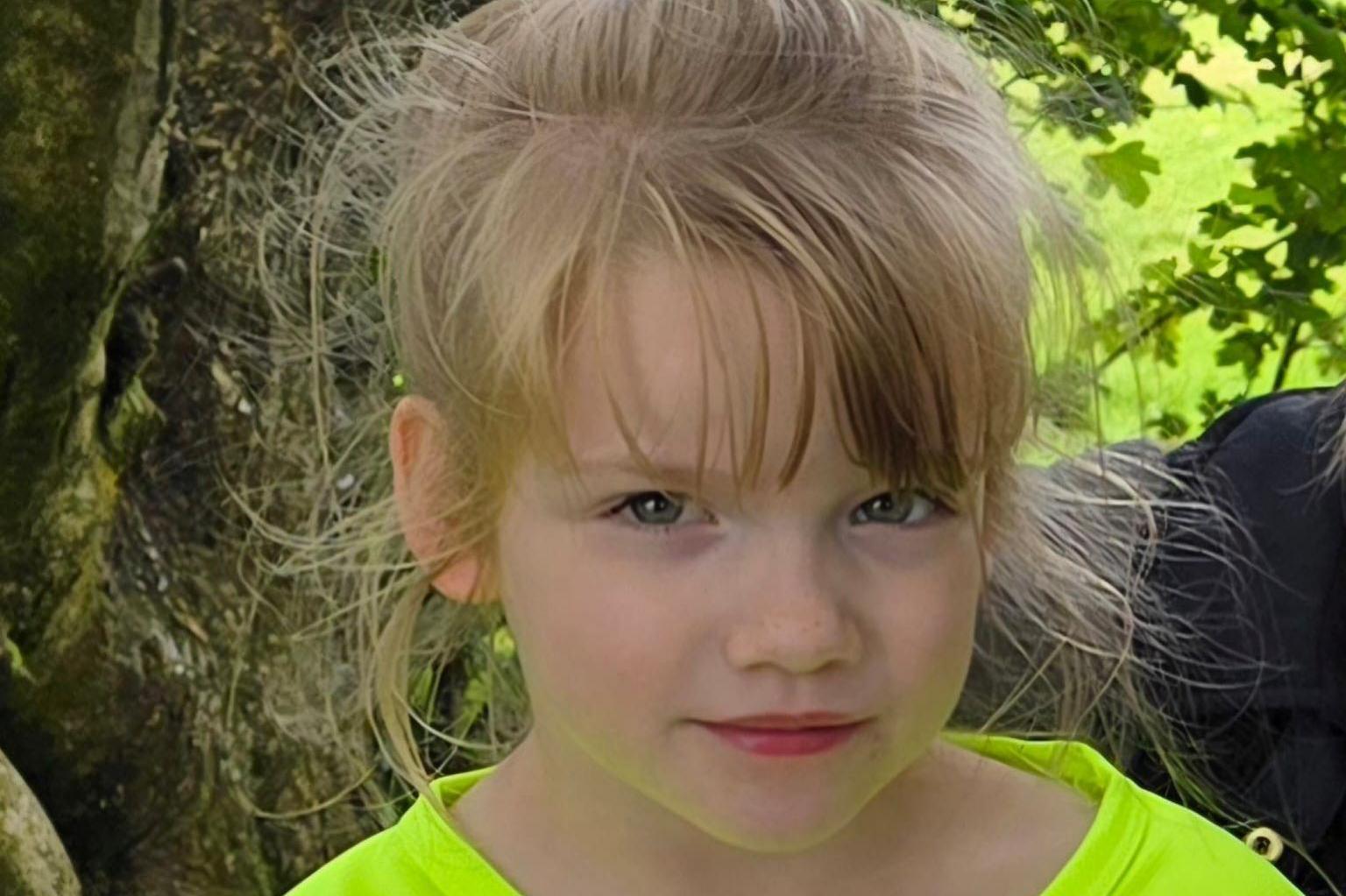 Hope looking directly at the camera. She is wearing a luminous green t shirt. She has blonde hair and blue eyes.