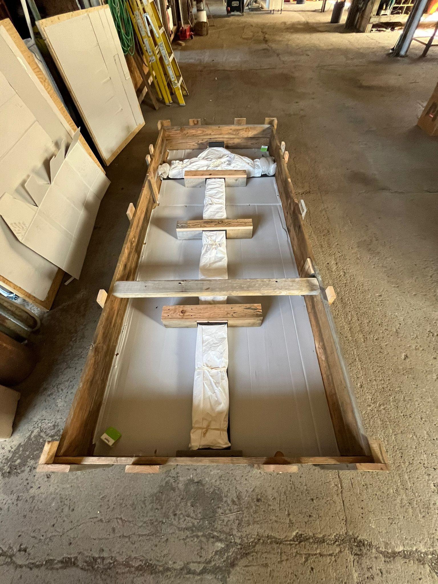 A cross wrapped in material sits inside a packing crate on the floor of a building