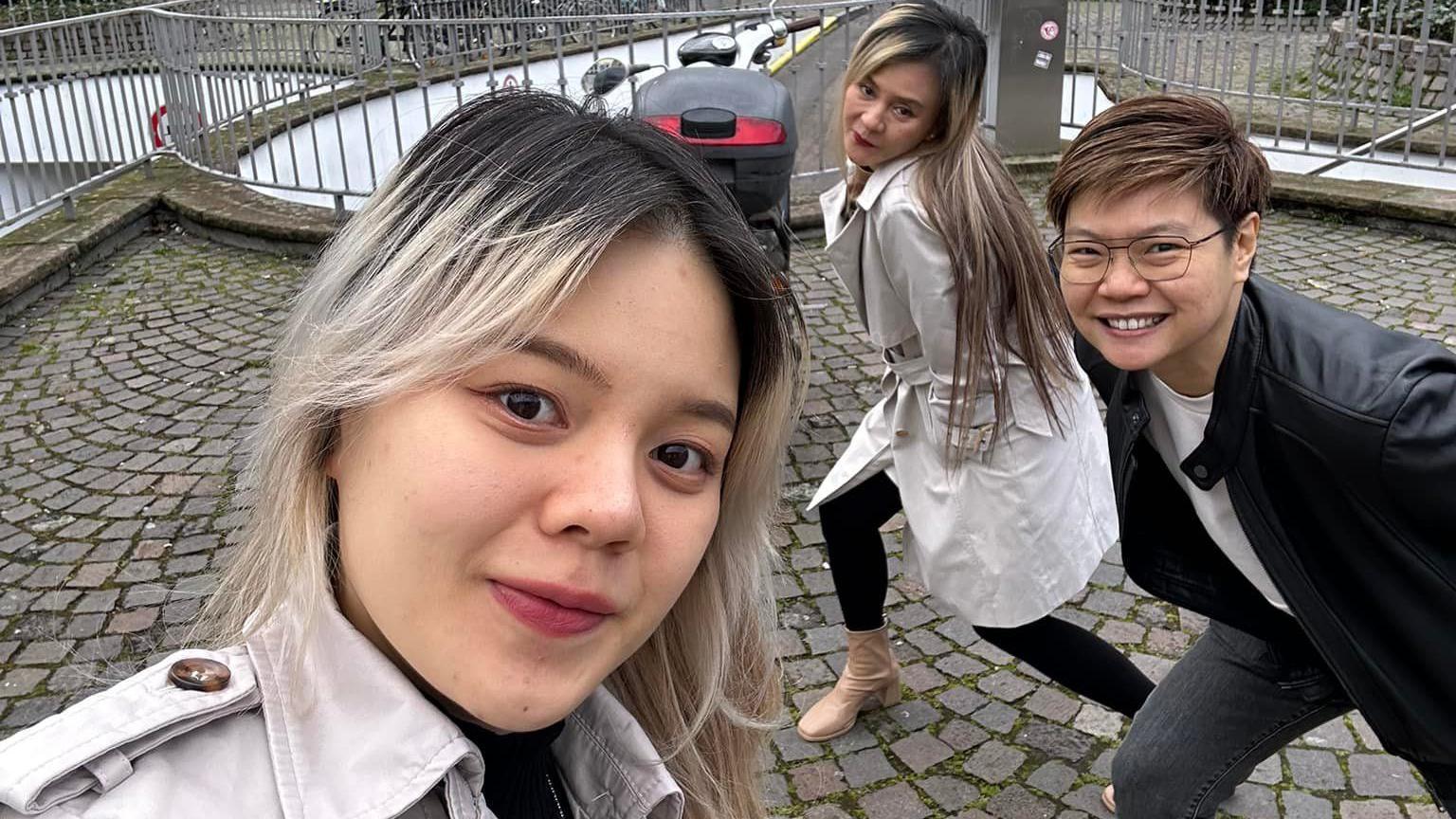 Rungtiwa and Phanlavee pose in the background as their daughter takes a selfie with them 