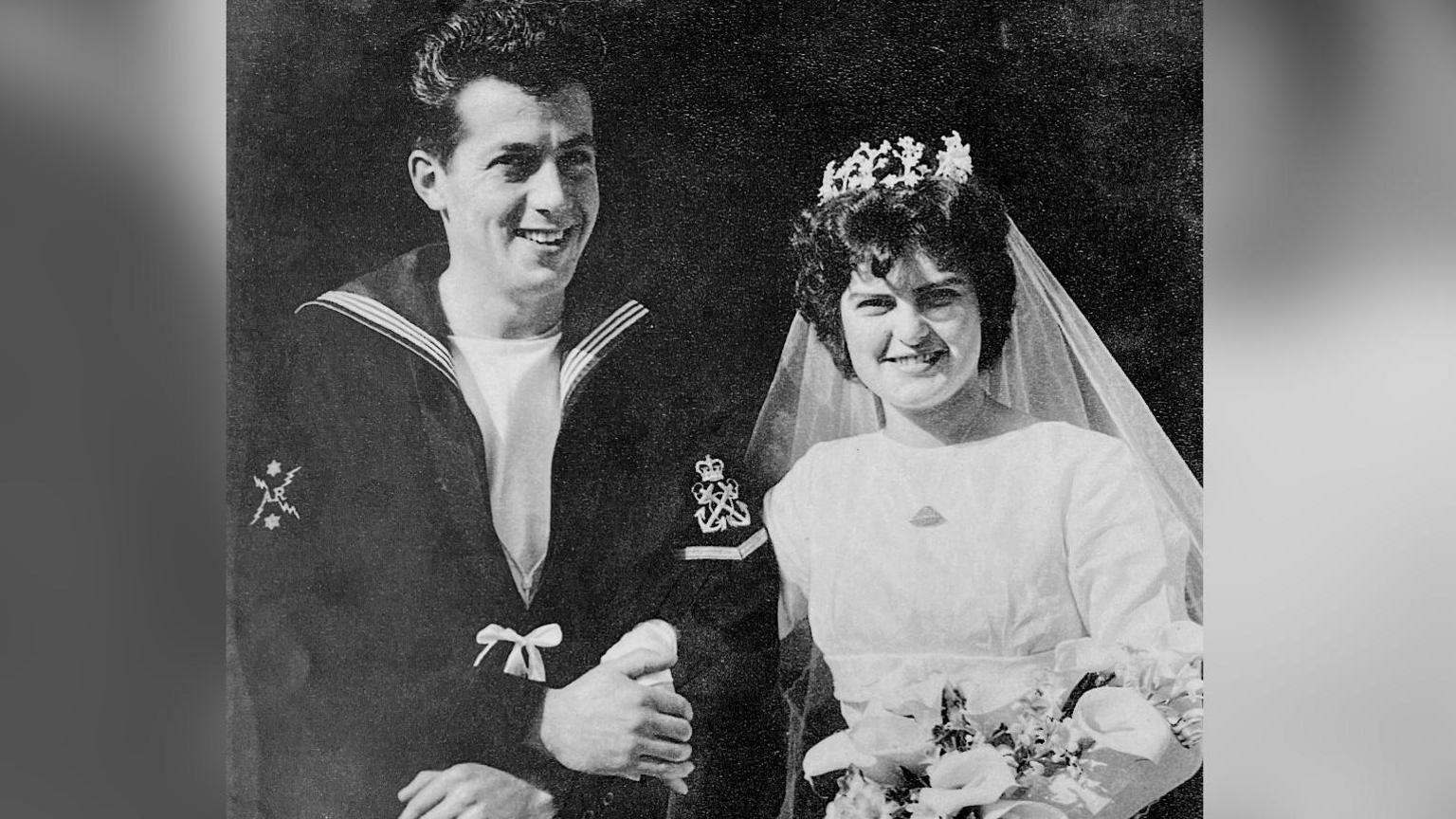 A wedding photo from 1959 of Ernest and Wendy Williams. She is wearing a white wedding dress and he is wearing a Navy uniform.