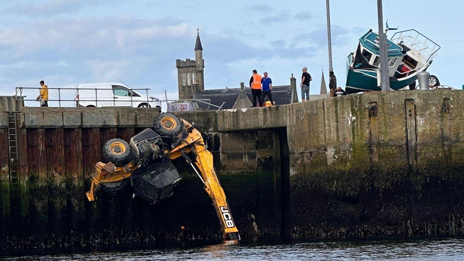 JCB vehicle dangling over the side of Fraserburgh harbour