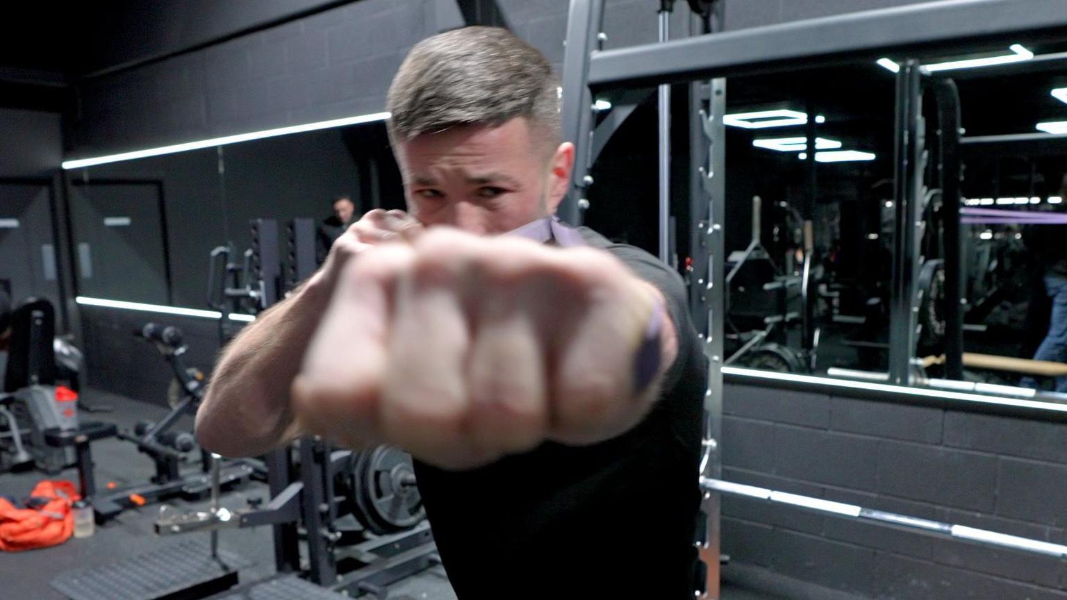 Bare-knuckle boxer Liam 'Rocky' Rees aims a punch at camera in his Swansea gym