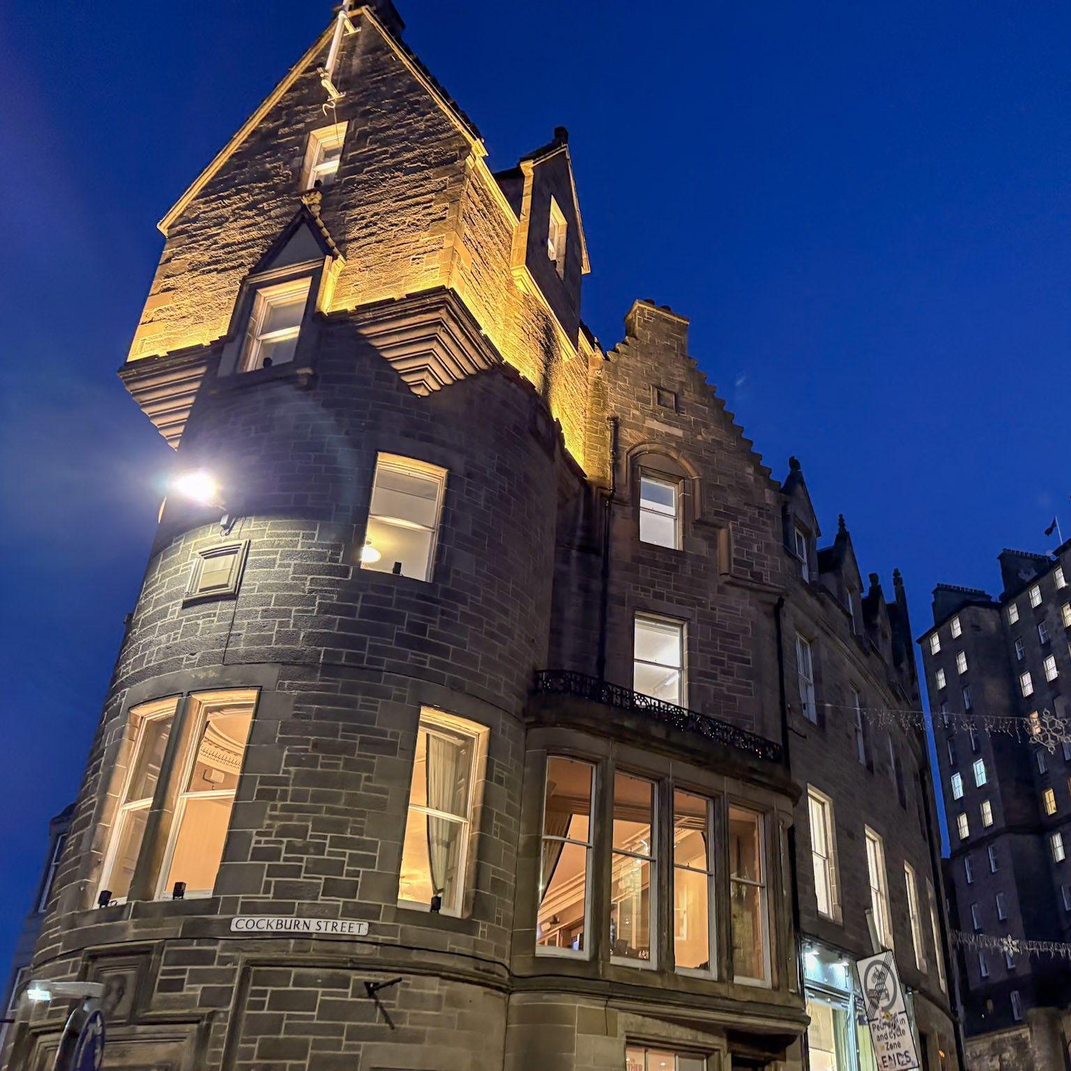 The picture has been taken from below the building, which is lit up and set against a dark blue sky.