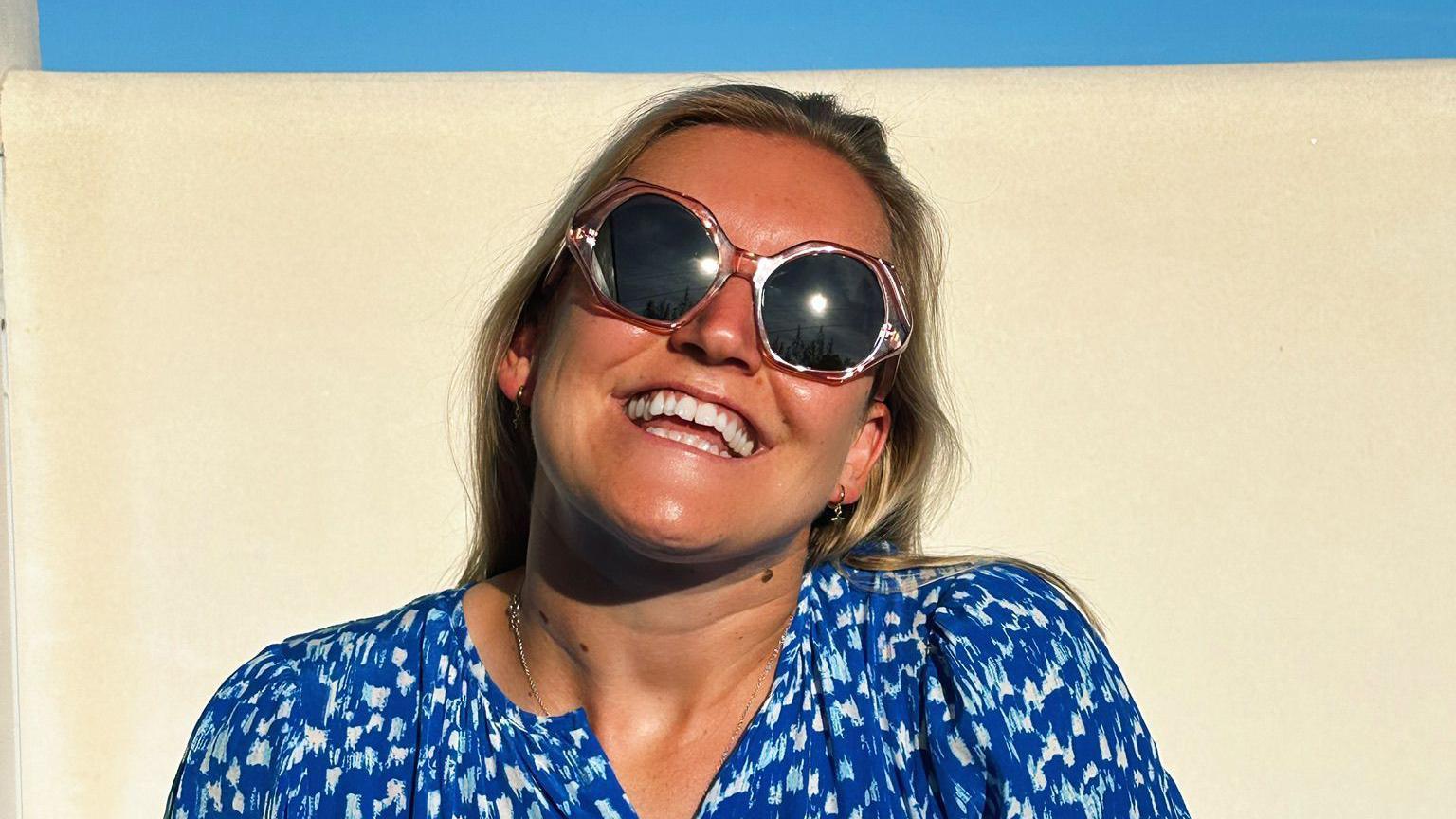 A woman in shades smiling in the sunshine