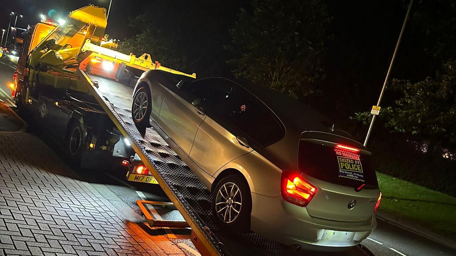 Seized car being loaded into a police van.