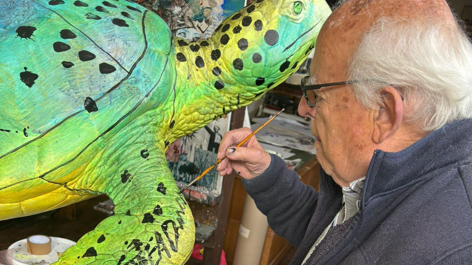 Ralph Steadman paints his turtle green and yellow, and signs his name in black 