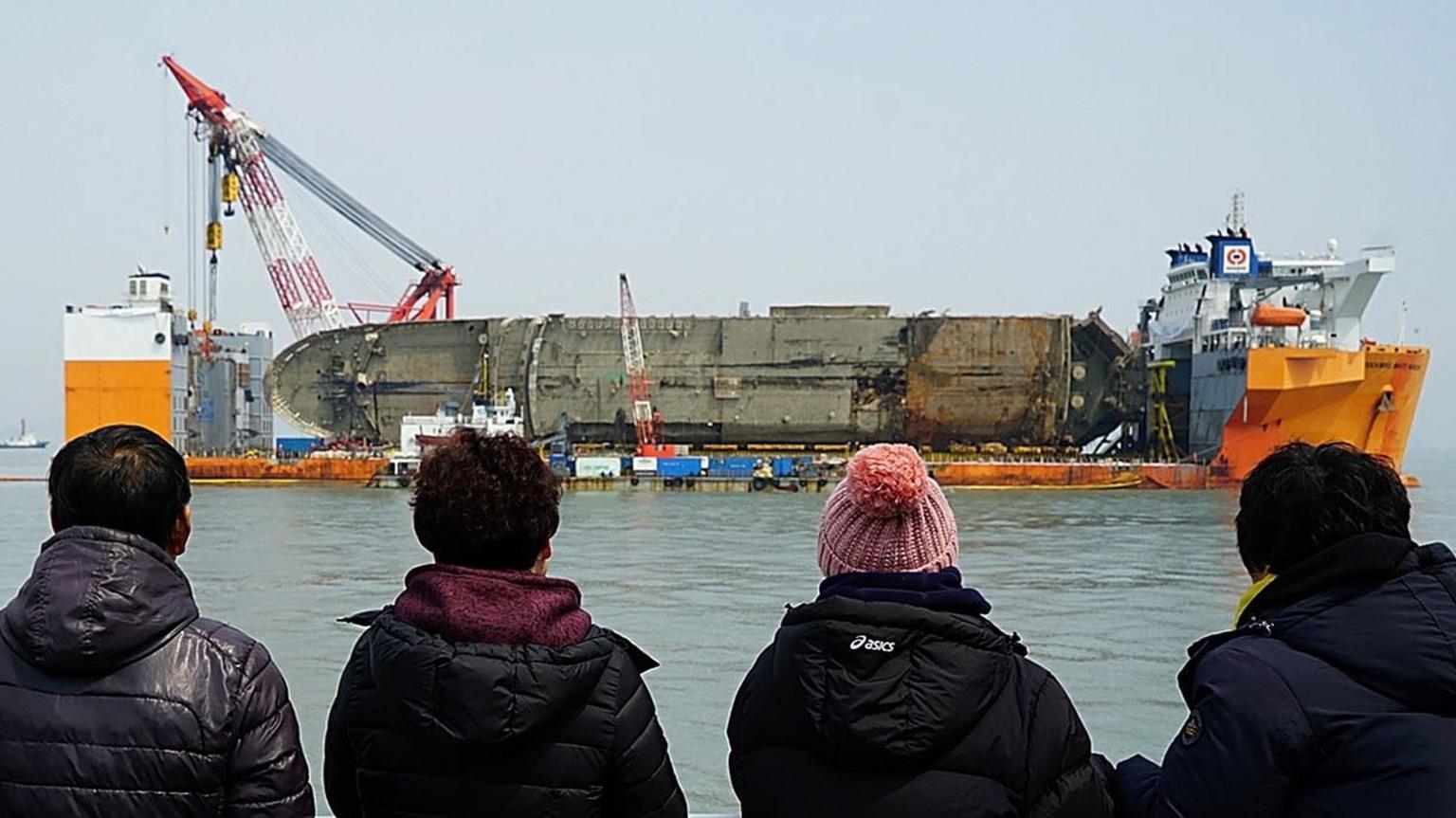 In this handout photo released by the South Korean Ministry of Oceans and Fisheries, relatives of the missing victims look at the raised ferry on 28 March 2017 off Jindo island, South Korea.