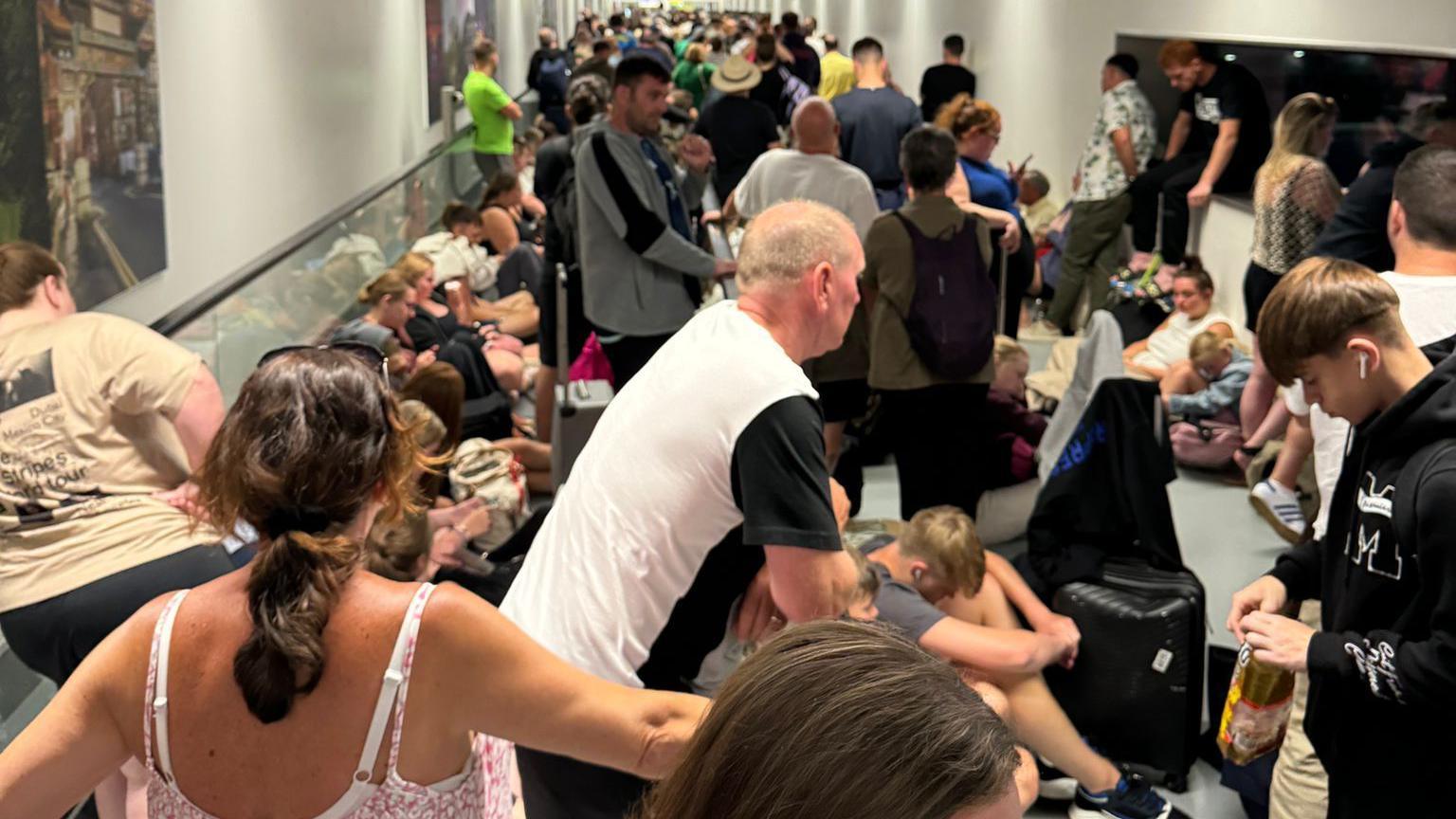 Passengers wait for news after disembarking a flight from Rhodes in the early hours of Sunday 