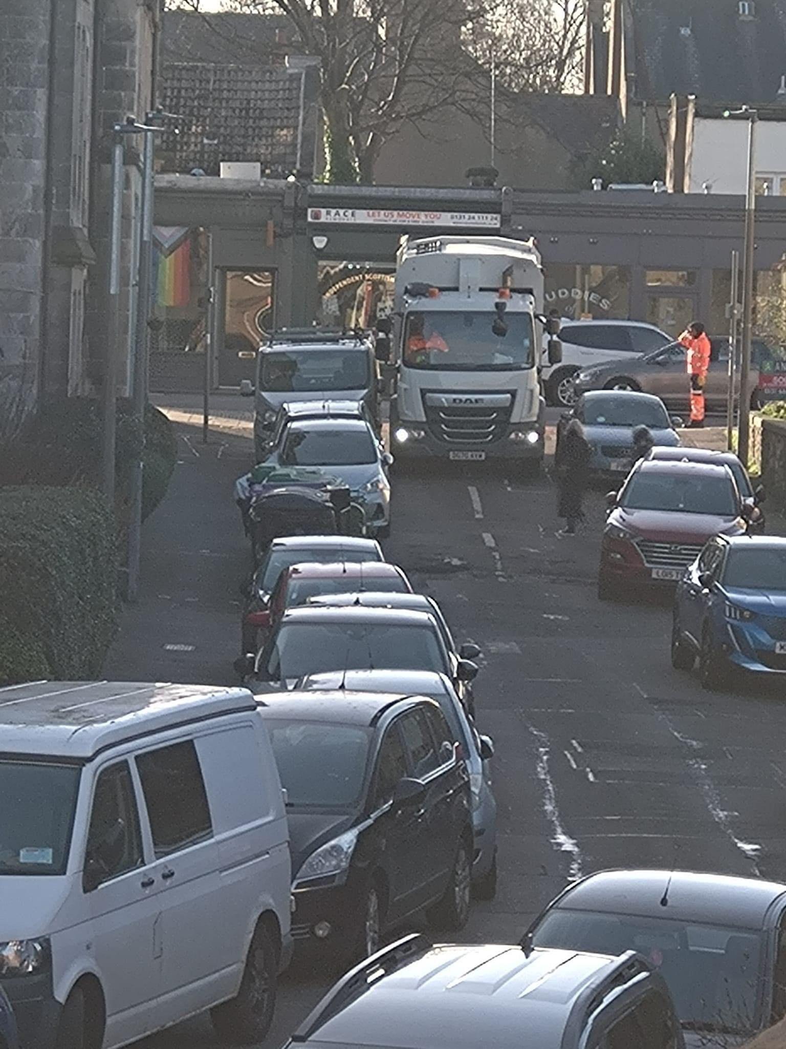 A bin lorry pictured reversing down a narrow street in Edinburgh on Friday - the vehicle was unable to pass cars parked on the road