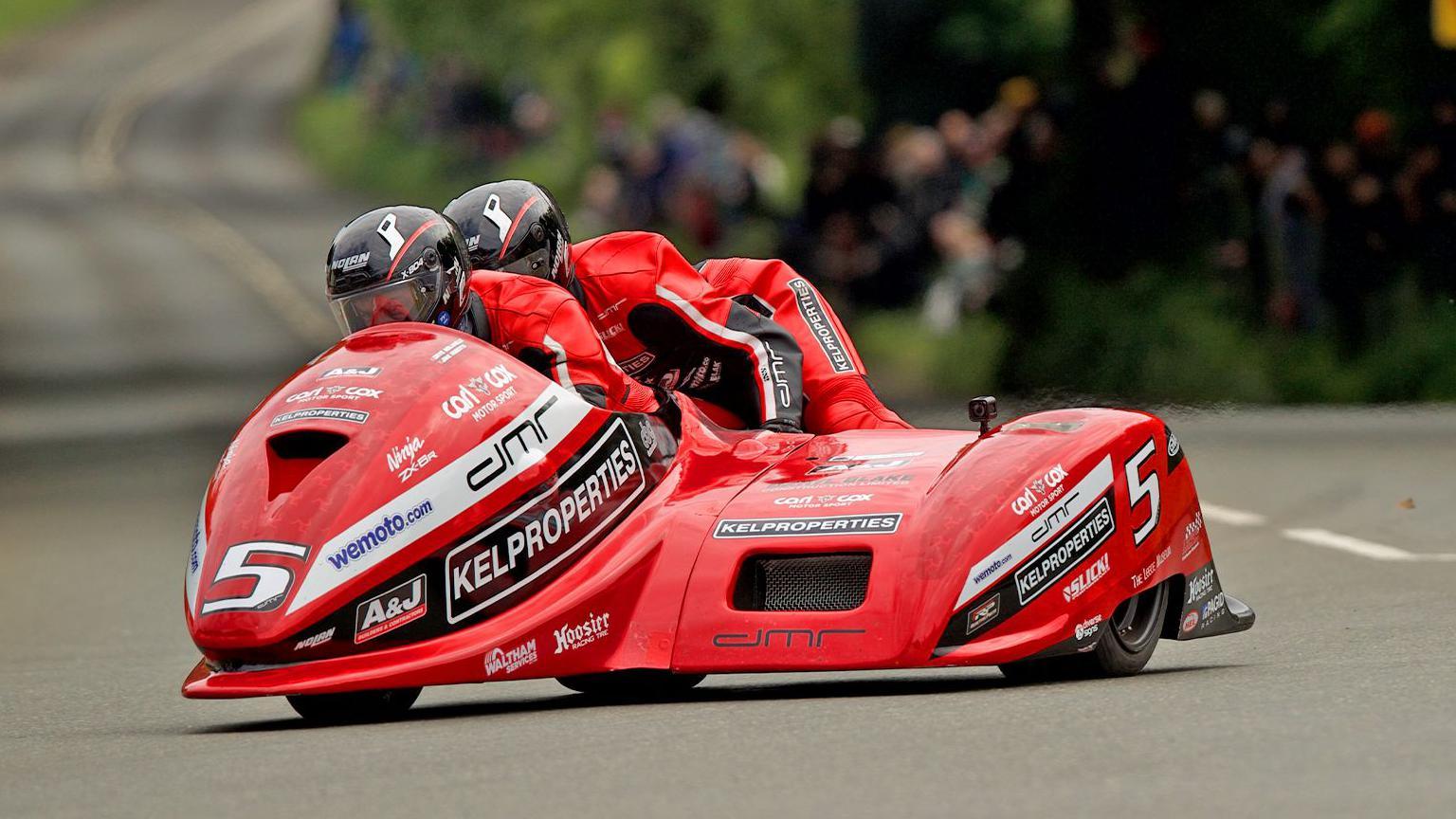 Red sidecar outfit on a race track with crowds in the background